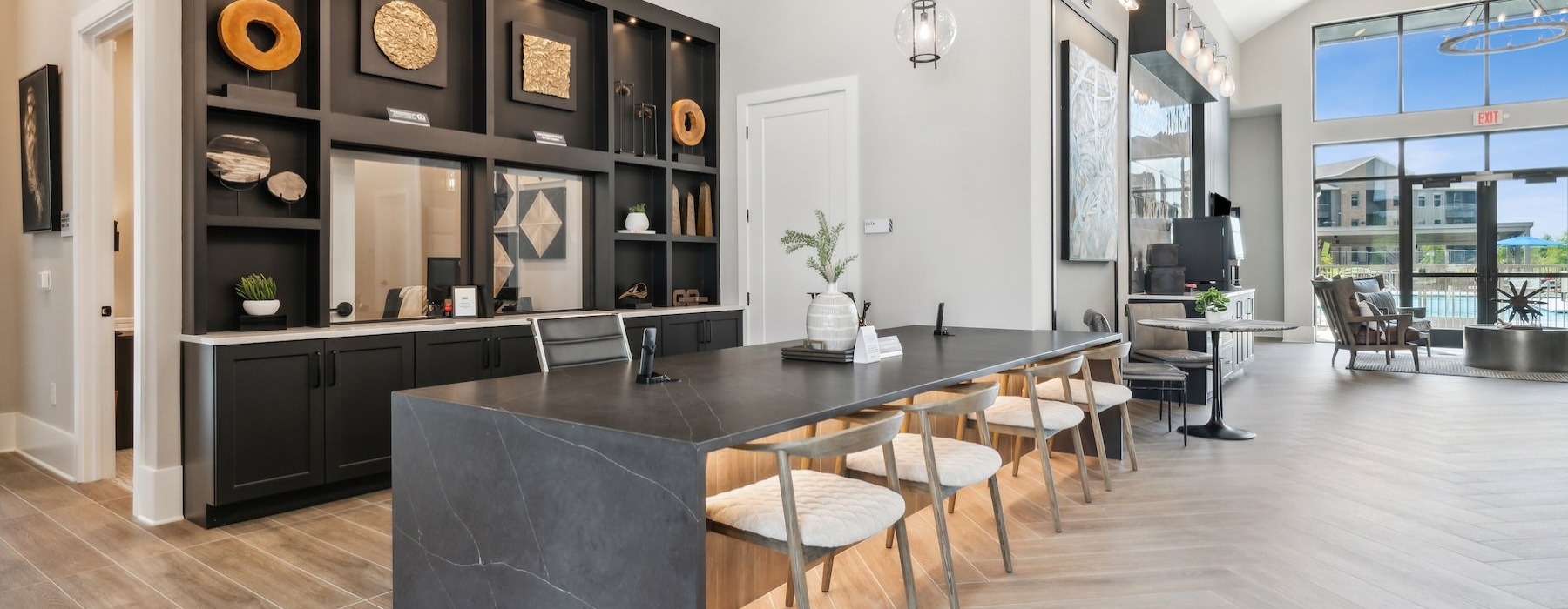 An interior view of a kitchen with a kitchen island countertop, a kitchen sink, barstool chairs, kitchen cabinetry, and stainless steel appliances including a fridge, oven, and a microwave at Alta Marine Creek apartments 76179 in Fort Worth, TX